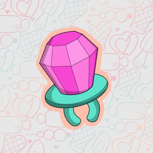 Puede incluir: Un anillo rosa y turquesa con un gran caramelo rosa en forma de diamante en la parte superior. El anillo está rodeado de un fondo blanco con un patrón de corazones y otras formas.