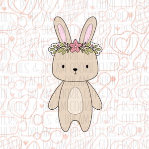 May include: A brown bunny cookie cutter with a floral crown. The bunny has a simple design with large ears, a small nose, and a rounded body. The crown is made of green leaves and pink flowers.