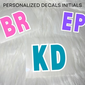 May include: Three white vinyl stickers with personalised initials. The first sticker has the initials "BR" in pink. The second sticker has the initials "EP" in purple. The third sticker has the initials "KD" in teal.