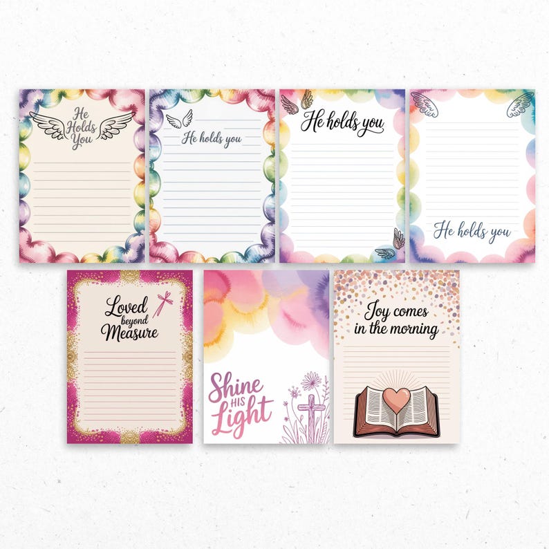 May include: A collection of lined stationery with watercolor designs and inspirational quotes. The stationery features phrases like "He Holds You," "Loved Beyond Measure," and "Joy Comes in the Morning." Each sheet has a decorative border with pastel colors and illustrations.