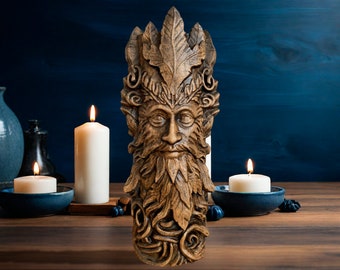 Pode incluir: Uma escultura de madeira detalhada de um Homem Verde com barba e coroa de folhas. A escultura é castanha e está sobre uma superfície de madeira, com velas acesas e tigelas de cerâmica azuis no fundo.