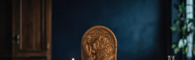 May include: A wooden carving of a mythical creature with intricate details. The carving is brown and has a textured surface. It is set against a dark blue background.