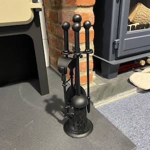 May include: Black fireplace tool set with a brush, poker, shovel, and tongs. The tools are mounted on a stand with a black finish.