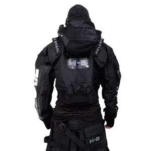 Puede incluir: Chaqueta t&aacute;ctica negra con capucha, m&uacute;ltiples bolsillos y correas. Texto blanco visible en la manga izquierda y la espalda, con las letras "H-G". El dise&ntilde;o sugiere una est&eacute;tica futurista o de inspiraci&oacute;n militar.