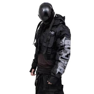 Puede incluir: Chaqueta t&aacute;ctica negra con m&uacute;ltiples bolsillos, correas y una capucha. La chaqueta presenta el texto "SURVIVAL" en gris en la manga derecha. La persona lleva un casco negro y pantalones negros.