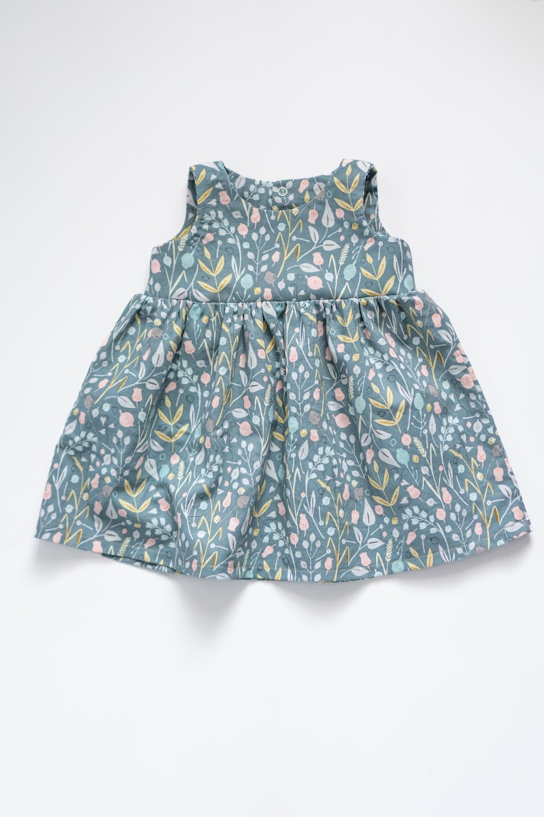 May include: A sleeveless, light blue dress with a floral print. The dress has a gathered skirt and a simple, round neckline.