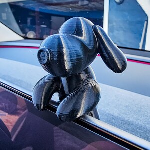 K&ouml;nnte beinhalten: Eine schwarze, 3D-gedruckte Hunde-Figur mit strukturierter Oberfl&auml;che. Der Hund hat gro&szlig;e, schlaffe Ohren und sitzt auf einer Metallstange. Die Figur ist ein dekoratives Objekt.