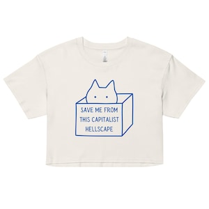 May include: A white cropped t-shirt with a blue outline of a cat in a box. The text "SAVE ME FROM THIS CAPITALIST HELLSCAPE" is printed on the shirt.