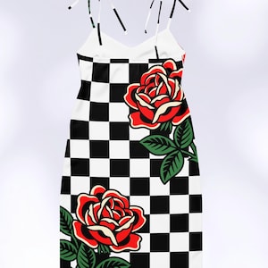 May include: A sleeveless dress featuring a black and white checkered pattern throughout. The garment is adorned with two large, vibrant red roses with green leaves and stems. It includes thin, adjustable tie-up shoulder straps at the top.