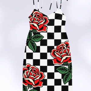 May include: A sleeveless dress featuring a black and white checkered pattern throughout. The garment is decorated with large, vibrant red roses with cream-colored highlights and green leaves. It includes thin, adjustable tie-up shoulder straps.