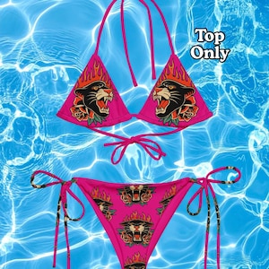 Peut inclure: Un ensemble de bikini rose vif avec un imprimé graphique répété représentant une tête de panthère noire entourée de flammes orange et jaunes et de roses rouges. Le haut est de style triangle avec des liens, et le bas a des liens latéraux. Texte Top Only.