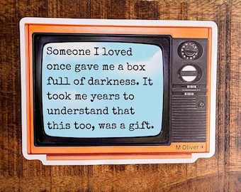 May include: A vintage-style television with an orange frame and a blue screen displaying a quote: "Someone I loved once gave me a box full of darkness. It took me years to understand that this too, was a gift." The quote is attributed to M Oliver.