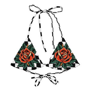 Puede incluir: Un top de bikini con un patrón de cuadros negros y blancos y un gráfico de una rosa roja en cada copa triangular. La prenda incluye tiras finas de cuadros a juego para anudar en el cuello y la espalda para un cierre ajustable.
