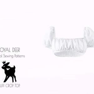 Peut inclure: Un haut court blanc à manches bouffantes. Le haut présente un col carré et un corsage froncé. L'image comprend également le texte "ROYAL DEER Digital Sewing Patterns" et une silhouette de cerf couronné.