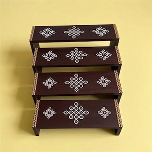 May include: A tiered, dark brown wooden shelf unit with four levels. Each level features white geometric designs and a decorative border. The unit is set against a yellow background, showcasing the handcrafted details and the contrast of colors.
