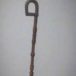 Könnte beinhalten: Ein Gehstock aus Holz mit einem geschnitzten Griff in Form eines D. Der Stock ist entlang seiner Länge mit geschnitzten Mustern verziert.