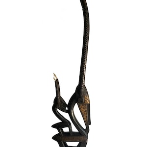 Puede incluir: Una escultura de madera tallada de color marrón oscuro con dos figuras estilizadas. Una figura es alta y delgada, con una superficie texturizada, mientras que la otra es más pequeña y está sentada. La escultura tiene una estética natural y orgánica.