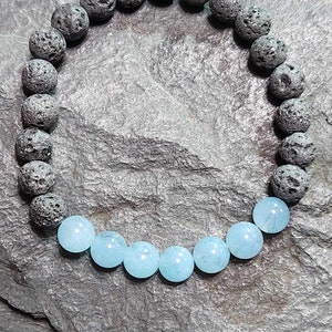 May include: A bracelet made of black lava rock beads and light blue aquamarine beads.