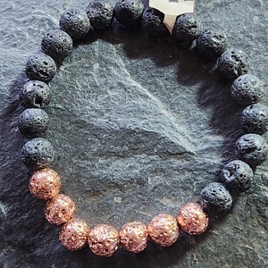 May include: A black lava rock bracelet with copper beads. The bracelet has a tag that says "Lava Love".