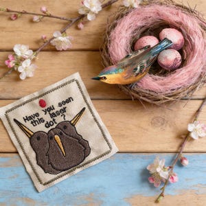 May include: A set of three ceramic mugs with a speckled, matte finish. Each mug features a different color: light blue, cream, and gray. The mugs have a simple, modern design and a comfortable handle.