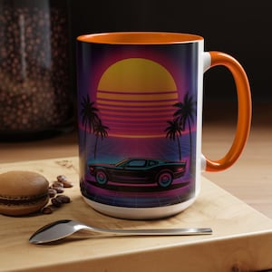 Op de afbeelding: Witte keramische mok met een oranje binnenkant en handvat. De mok heeft een retro design met een auto, palmbomen en een zonsondergang. Het ontwerp is in tinten zwart, paars, oranje en blauw.