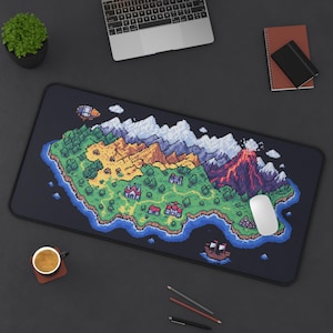 May include: Black rectangular mousepad featuring a pixelated island map design with mountains, a volcano, and a ship. The mousepad has a black border and a white mouse is on the right side. A laptop, coffee cup, and notebook are also visible.