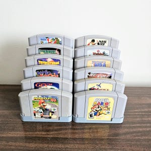 May include: A stack of 10 Nintendo 64 game cartridges, including titles such as Starfox 64, Tetrisphere, Banjo Kazooie, Gex 64, Mario Kart 64, and Paper Mario.