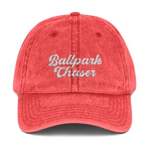 May include: Red vintage baseball cap with white embroidered text that reads "Ballpark Chaser".