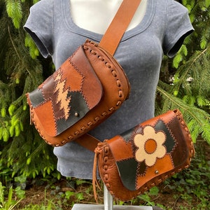 Könnte beinhalten: Zwei braune Leder-Gürteltaschen im Patchwork-Stil mit einem Blumendesign auf einer. Die Gürteltaschen werden von einem Mannequin getragen, das ein graues Shirt trägt.