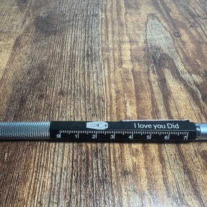 May include: A black multi-tool pen with a ruler, a stylus tip, and the inscription "I love you Did".