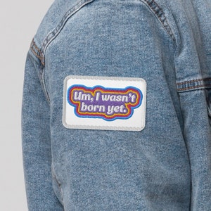 May include: A blue denim jacket with a white sherpa collar and a patch on the left sleeve that says "Um, I wasn't born yet."