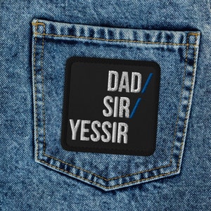May include: Light blue denim jeans with a black patch on the back pocket. The patch has the words "DAD SIR YESSIR" in white and blue lettering.