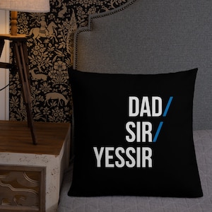 May include: Black throw pillow with white text that reads "DAD/SIR/YESSIR" with a blue slash between each word.