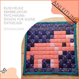 Könnte beinhalten: Ein Patchwork-Quilt mit einem pixeligen Dinosaurier-Design. Er besteht aus Quadraten in Rosa, Blau und Marineblau mit einem türkisfarbenen Rand. Der Text "Kuschelige Krabbeldecke: Patchwork-Design für kleine Entdecker Dinosaurier" ist sichtbar.