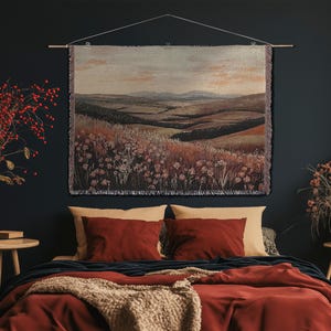 May include: A landscape tapestry featuring a rural scene with hills and fields, in shades of brown, green, and beige. The tapestry hangs above a bed with red bedding and pillows, creating a warm and inviting atmosphere. The tapestry is approximately 100 cm wide.