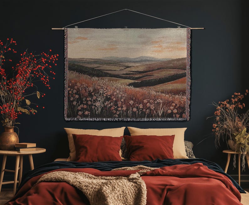 May include: A landscape tapestry featuring a rural scene with hills and fields, in shades of brown, green, and beige. The tapestry hangs above a bed with red bedding and pillows, creating a warm and inviting atmosphere. The tapestry is approximately 100 cm wide.