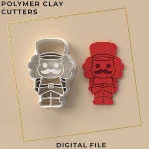 May include: Two polymer clay cutter designs shaped like nutcrackers. One is white and the other is red. The cutters have detailed features, including hats, mustaches, and belts. The text "POLYMER CLAY CUTTERS" and "DIGITAL FILE" are visible.
