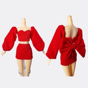 May include: A red two-piece outfit with a crop top and a skirt. The top has long, puffy sleeves and a sweetheart neckline. The skirt is a mini skirt with a bow detail on the back.