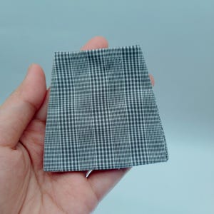 May include: A small, gray and white checkered fabric square.