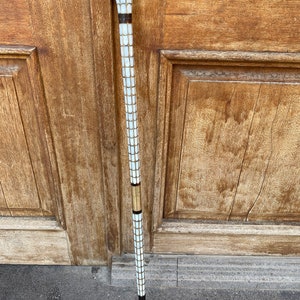 Puede incluir: Un bast&oacute;n blanco y dorado con una parte superior decorativa. El bast&oacute;n est&aacute; hecho de madera y tiene un patr&oacute;n blanco y dorado.