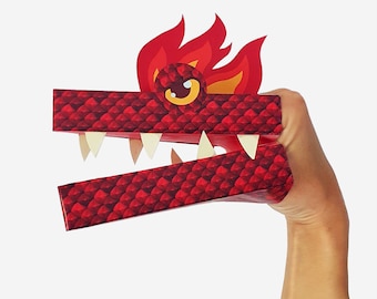 Puede incluir: Marioneta de dragón de papel rojo con una melena de fuego y una sonrisa de dientes. La marioneta está sostenida por una mano, lista para jugar.