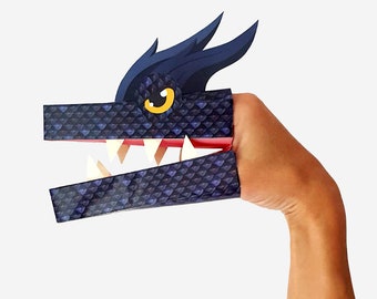 Puede incluir: Un títere de dedo negro con forma de dragón con una boca roja y dientes blancos. El dragón tiene un ojo amarillo y escamas azules.