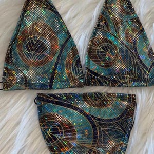 Puede incluir: Un bikini de color turquesa, dorado y negro iridiscente con un estampado de plumas de pavo real.
