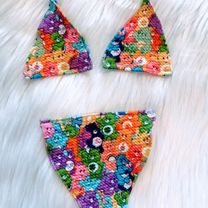 May include: A colorful bikini with a Care Bears print. The top is a triangle style and the bottom is a cheeky cut.