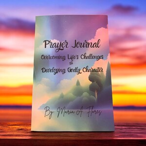 May include: A book titled "Prayer Journal: Overcoming Life's Challenges and Developing Godly Character" by Maria A. Flores. The cover features a colorful, abstract landscape with clouds and trees.