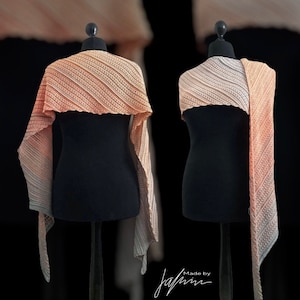 Puede incluir: Dos chales de ganchillo en un degradado de colores melocotón y crema, expuestos en maniquíes. Los chales están hechos con un delicado patrón de punto y tienen una forma fluida y drapeada. Los chales están etiquetados con "Made by JaPri".