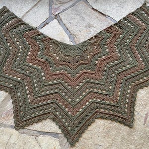 Op de afbeelding: Een gehaakte sjaal met een stervormig patroon in tinten groen en bruin.