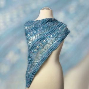 May include: A blue and purple crocheted shawl with a lacy pattern. The shawl is draped over a white mannequin.