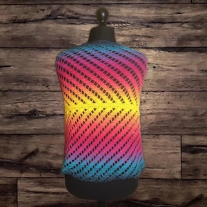 Könnte beinhalten: Ein Regenbogen-Häkeltop mit diagonalem Muster. Das Top wird auf einem hölzernen Mannequin präsentiert.