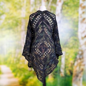 May include: A black and dark green crocheted shawl with an intricate diamond-shaped pattern. The garment features an openwork design with varied stitch textures, creating a geometric structure that drapes from the shoulders to a pointed hem.